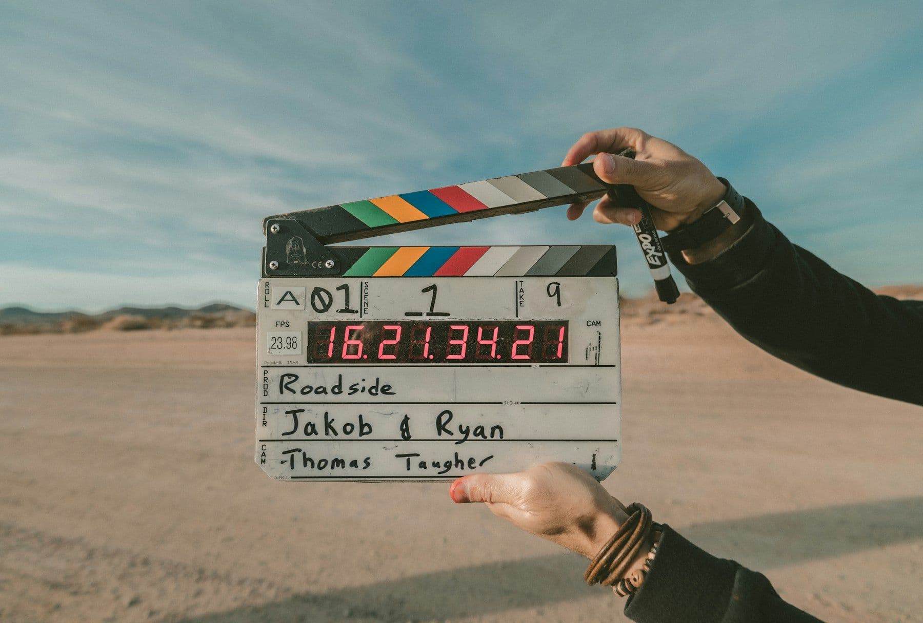 Hand holding a film clapperboard over a desert landscape