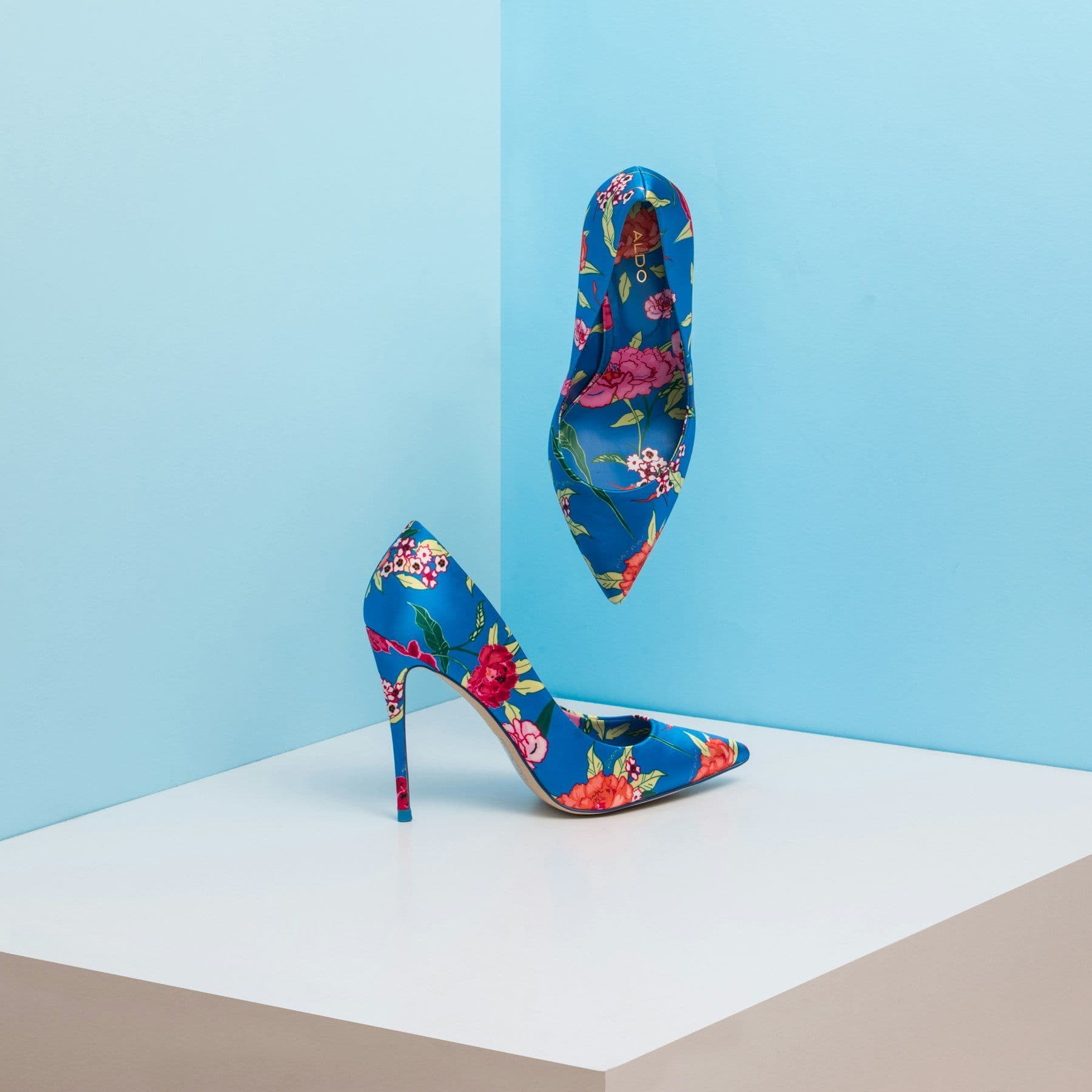Pair of floral-print stiletto heels on a white plinth