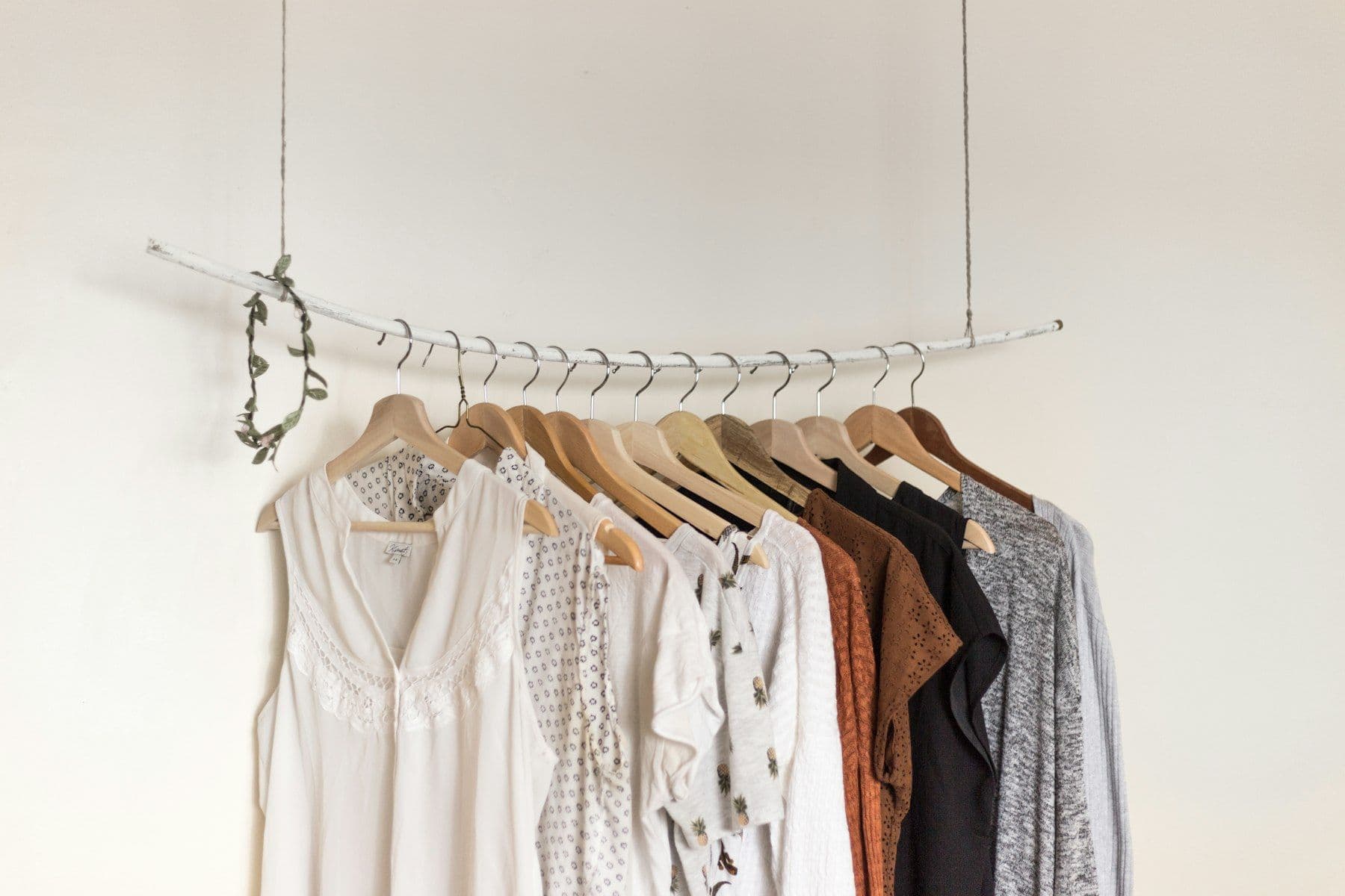 Minimal rail of white and neutral blouses on wooden hangers