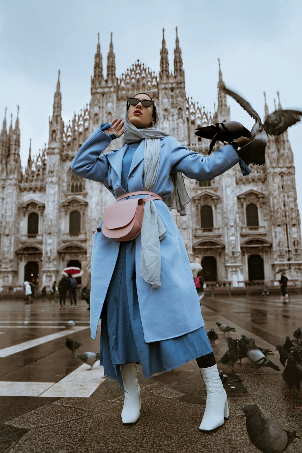 Street style outside a gothic cathedral, pale blue coat and white boots