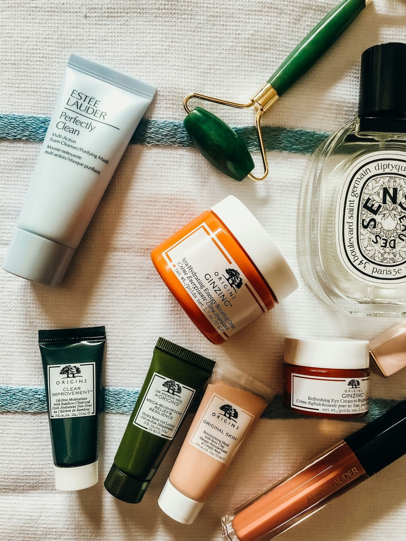 Skincare tubes, jars and a facial roller on linen