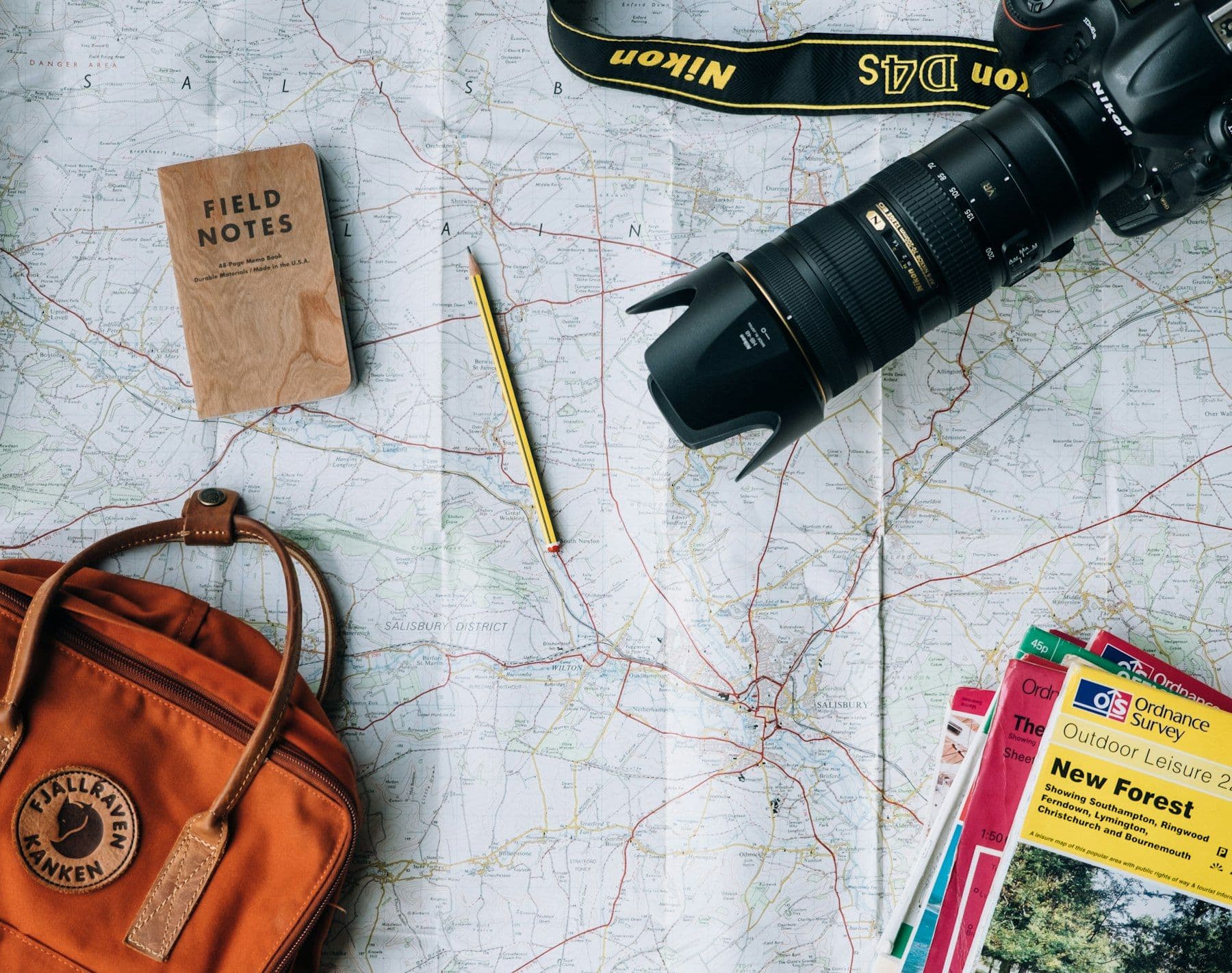 Map, notebook, camera and backpack laid out for travel