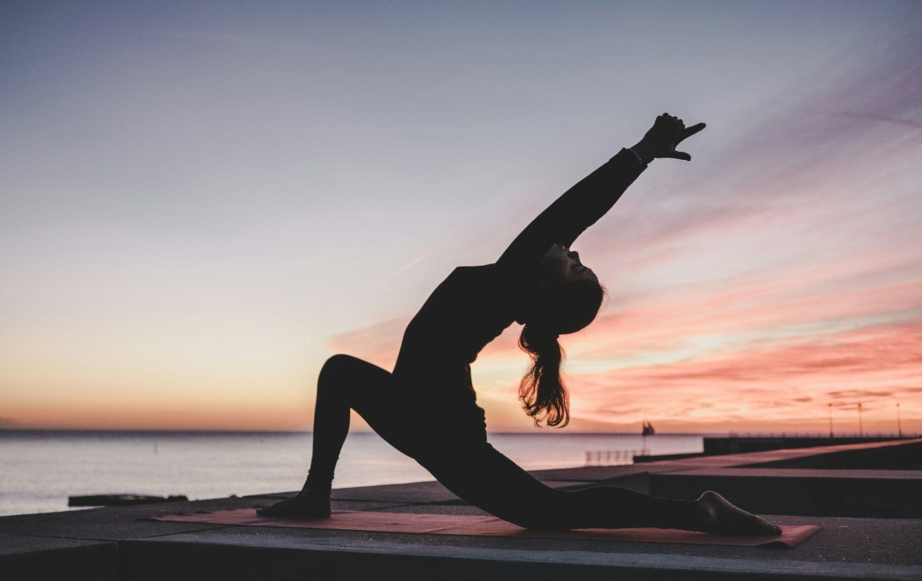 Silhouette of a person in a yoga pose at sunset