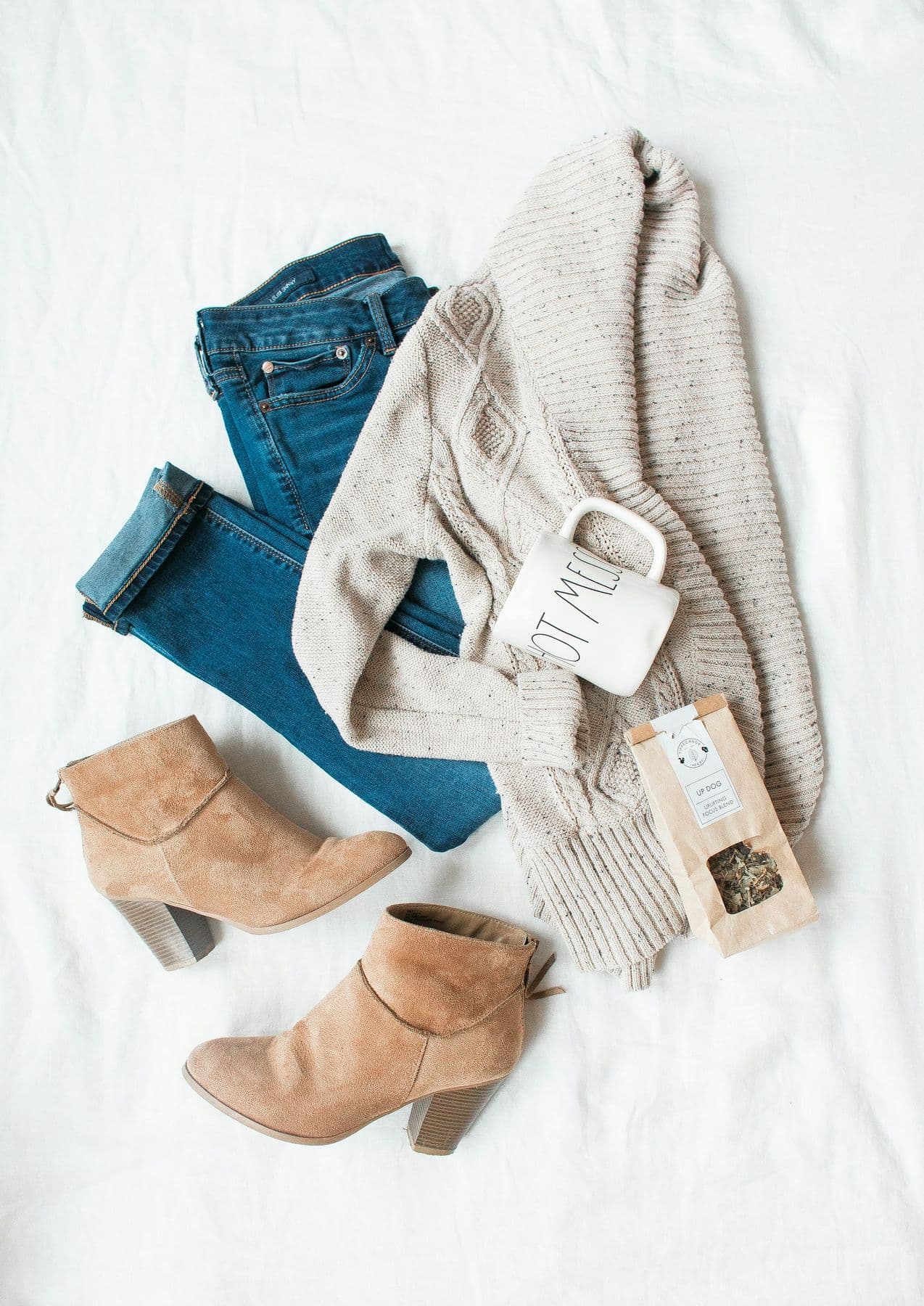 Flat lay of jeans, a cardigan and suede ankle boots