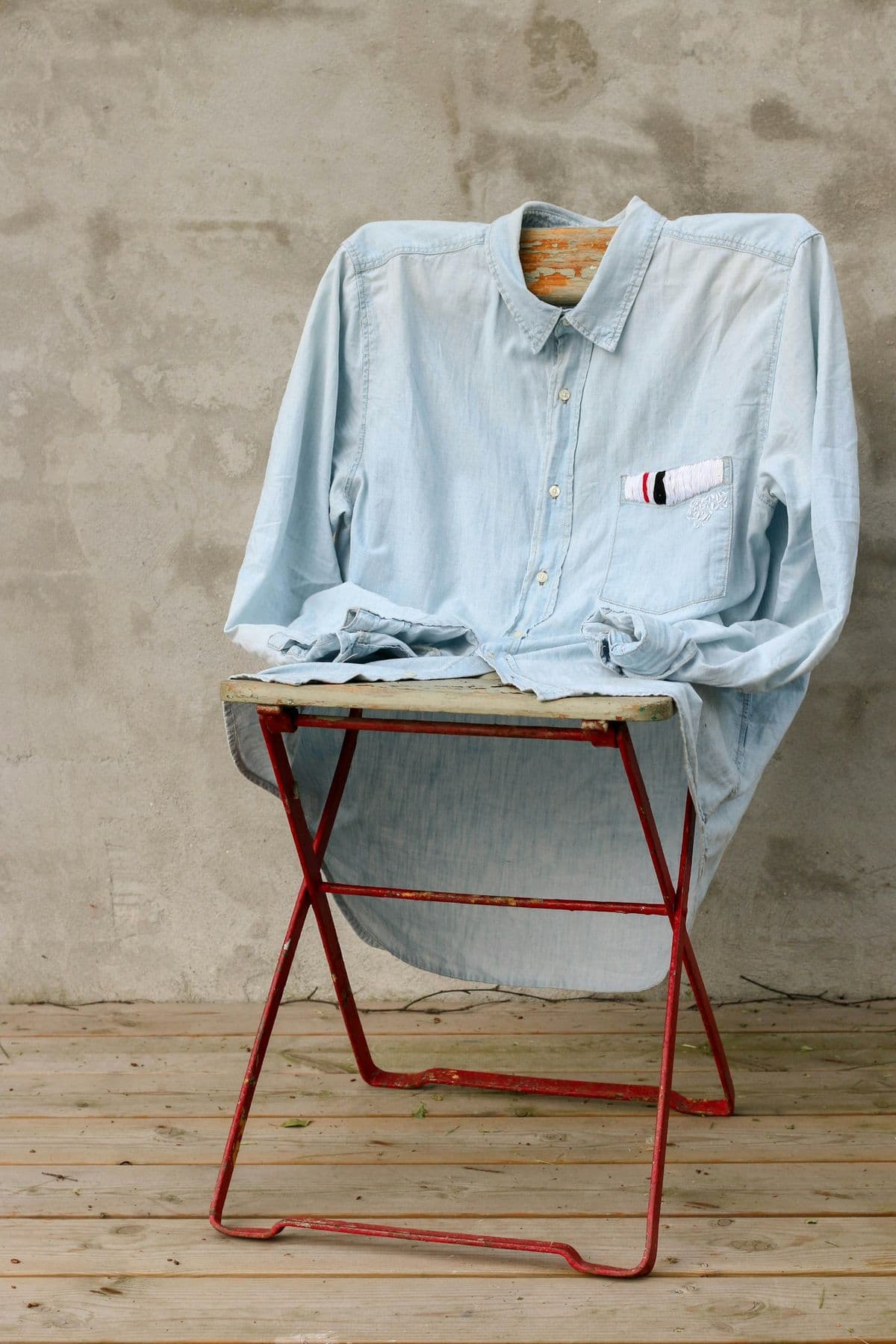 Pale denim shirt draped over a red folding chair