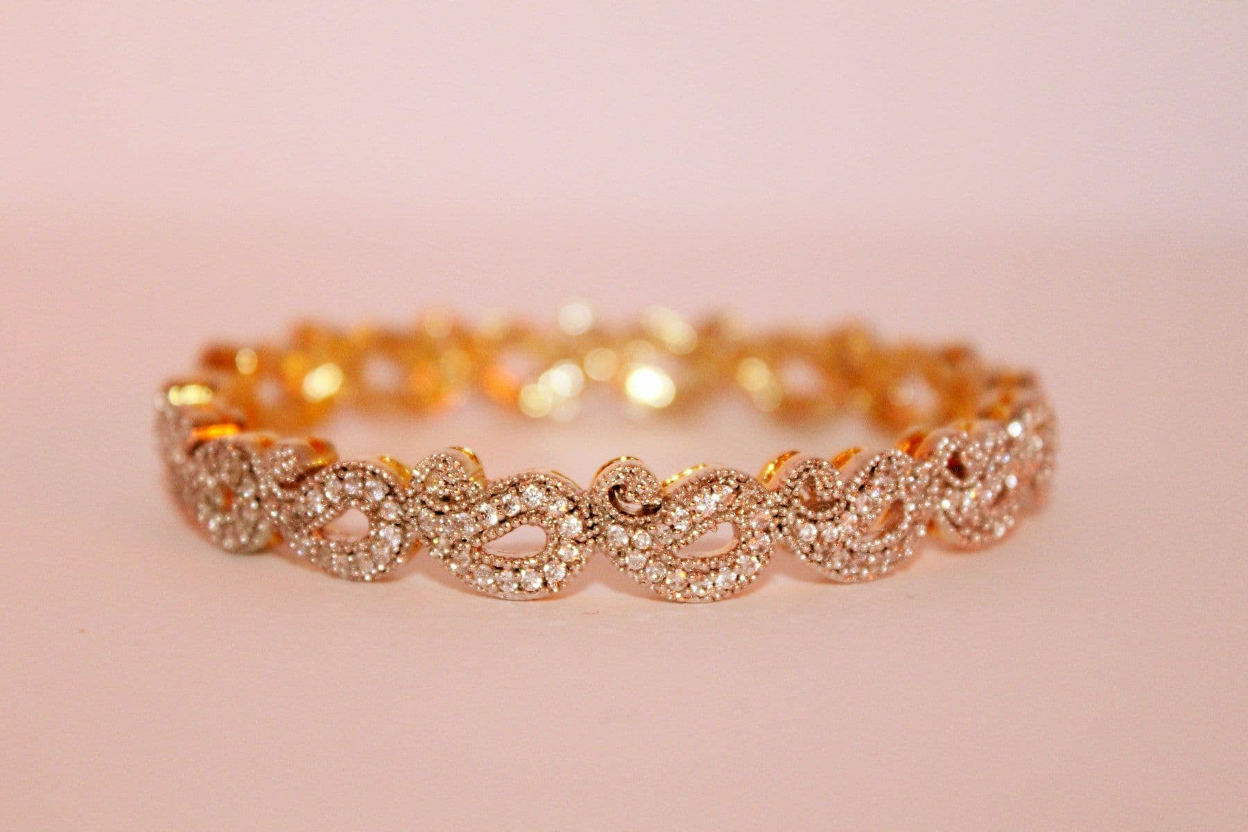 Gold chain bracelet on a blush background