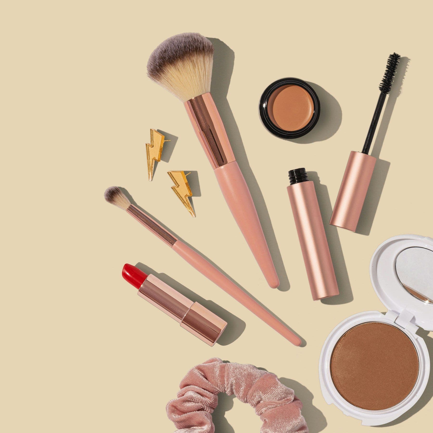 Brushes, lipstick and powder compacts on a beige background