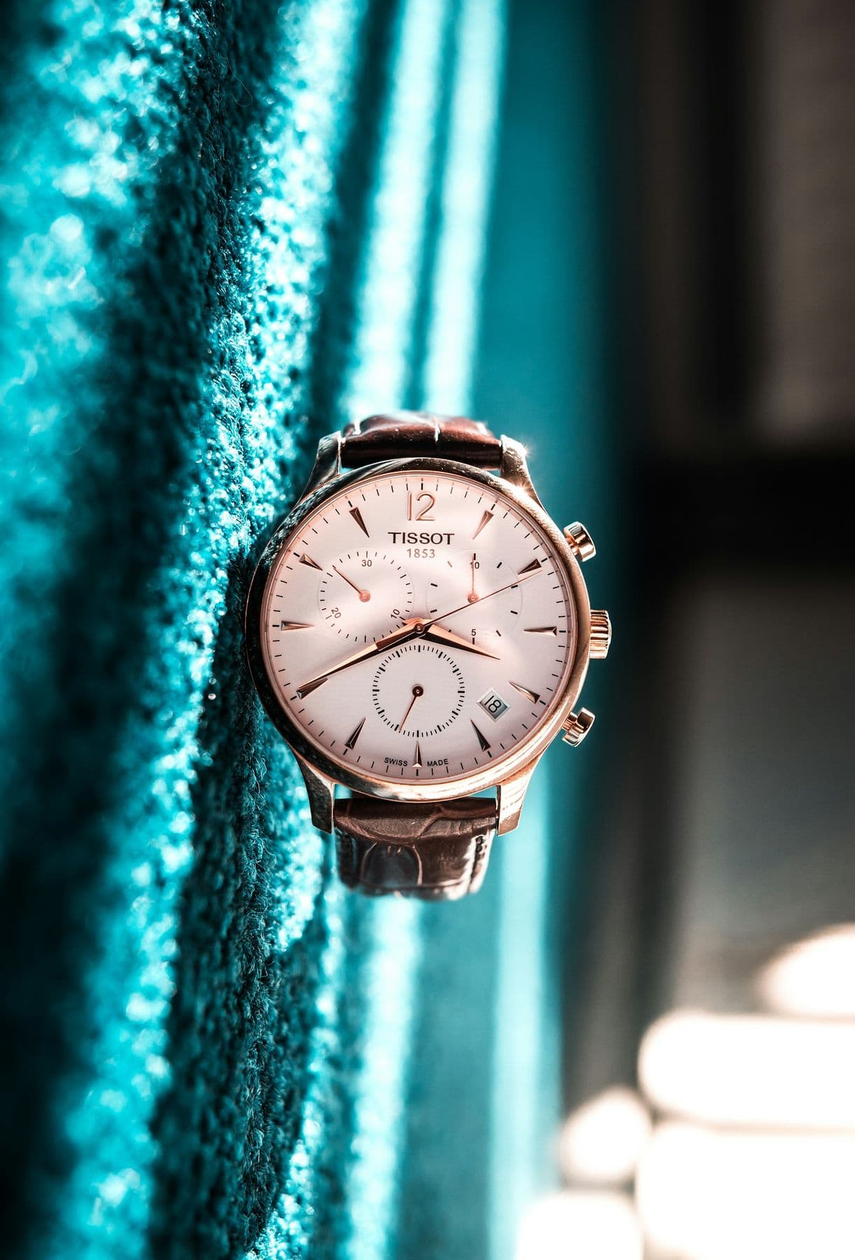 Rose-gold watch against a teal curtain