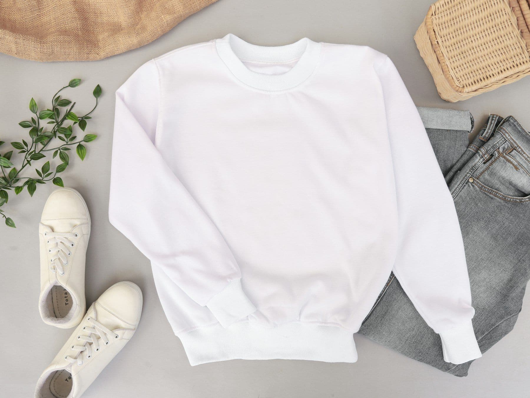 Flat lay of a white sweatshirt, sneakers and a woven basket