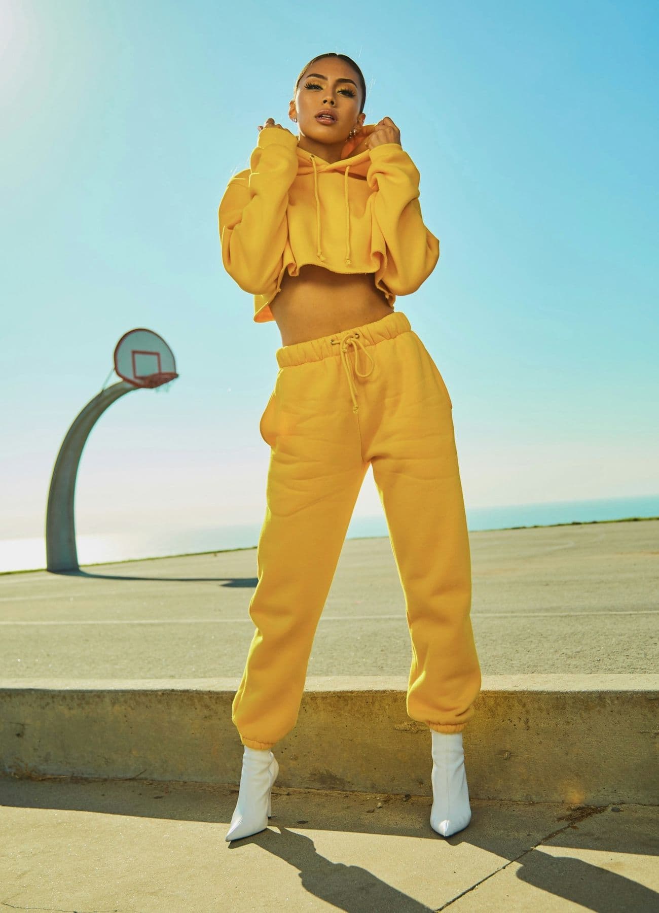 Woman in a yellow tracksuit and white boots by the sea